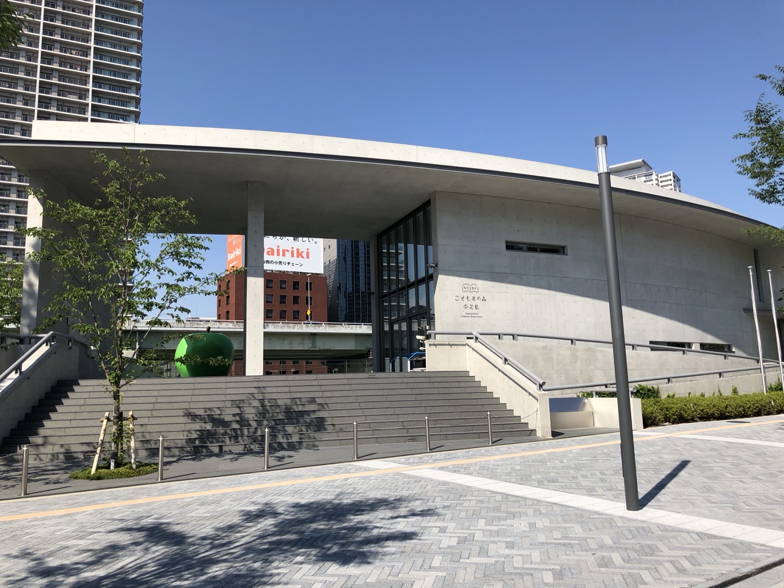 こども本の森 中之島の正面。弓なりに反ったコンクリートの壁が、川沿いの公園に呼応する。
