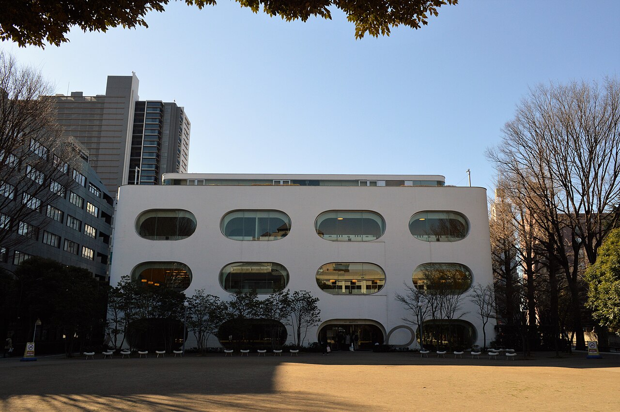 白い箱に楕円の窓が並ぶ、武蔵野プレイスの外観。武蔵境の公園に面して立つ。